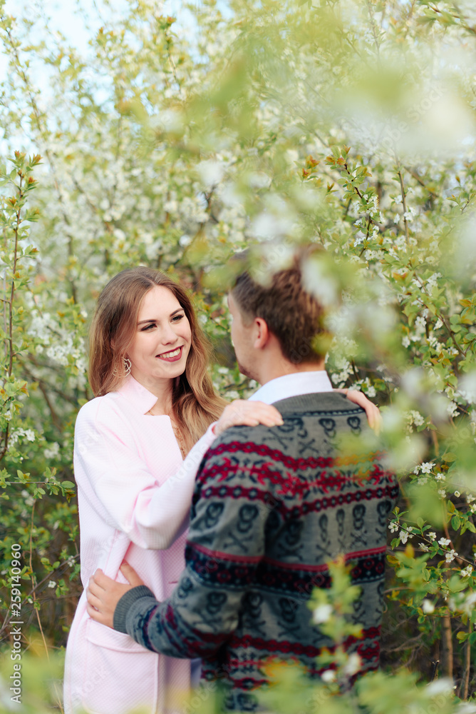 a young couple in love cuddles against the background of blooming spring cherry orchards 1 a young couple in love cuddles against the background of blooming spring cherry orchards 1
