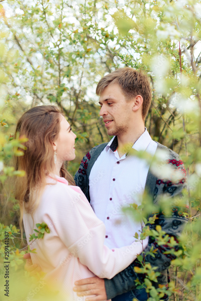 a young couple in love cuddles against the background of blooming spring cherry orchards 1 a young couple in love cuddles against the background of blooming spring cherry orchards 1