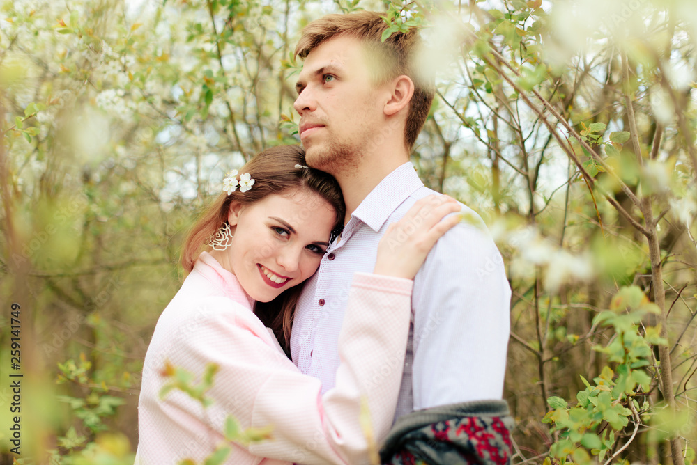 a young couple in love cuddles against the background of blooming spring cherry orchards 1 a young couple in love cuddles against the background of blooming spring cherry orchards 1