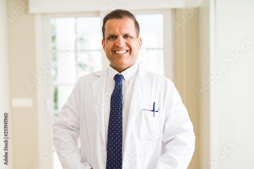 Middle age man wearing white medical coat and smiling