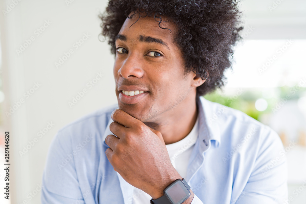 Handsome african american man with afro hair with hand on chin thinking about question, pensive expression. Smiling with thoughtful face. Doubt concept. Handsome african american man with afro hair with hand on chin thinking about question, pensive expression. Smiling with thoughtful face. Doubt concept.