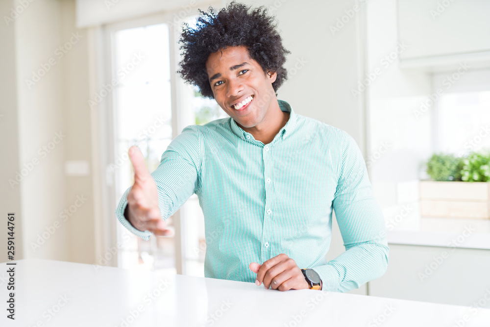 African American business man wearing elegant shirt smiling friendly offering handshake as greeting and welcoming. Successful business.