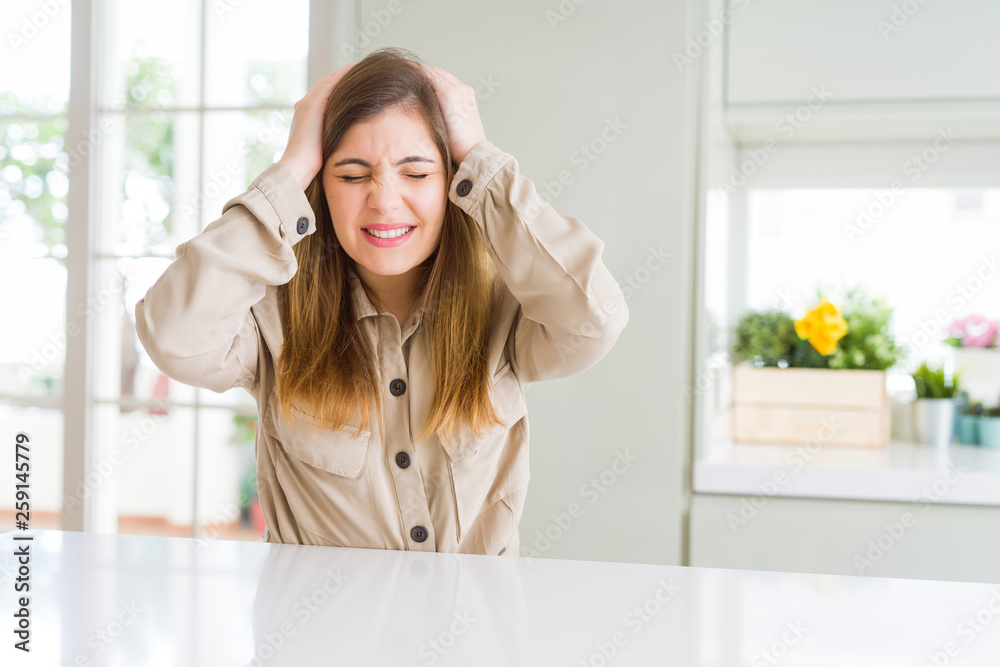 Beautiful young woman at home suffering from headache desperate and stressed because pain and migraine. Hands on head. Beautiful young woman at home suffering from headache desperate and stressed because pain and migraine. Hands on head.