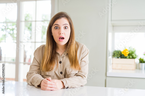 Beautiful young woman at home afraid and shocked with surprise expression, fear and excited face.