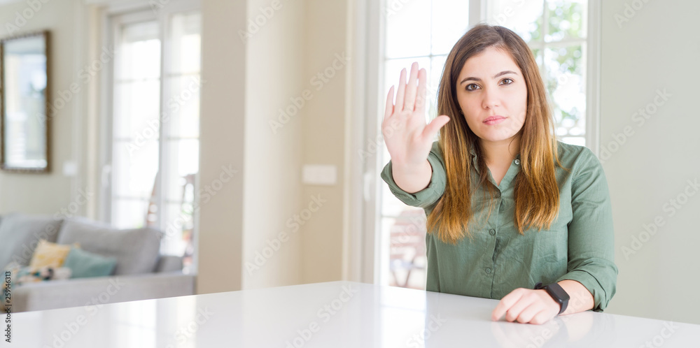 Beautiful young woman at home doing stop sing with palm of the hand. Warning expression with negative and serious gesture on the face. Beautiful young woman at home doing stop sing with palm of the hand. Warning expression with negative and serious gesture on the face.