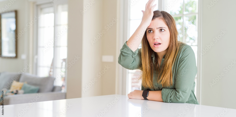 Beautiful young woman at home surprised with hand on head for mistake, remember error. Forgot, bad memory concept. Beautiful young woman at home surprised with hand on head for mistake, remember error. Forgot, bad memory concept.