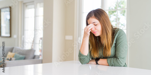 Beautiful young woman at home tired rubbing nose and eyes feeling fatigue and headache. Stress and frustration concept.