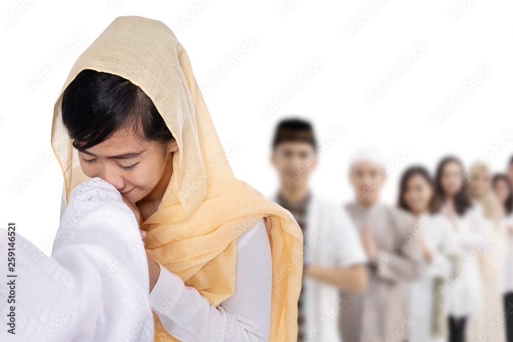 portrait of asian muslim woman with hijab kissing hand at eid mubarak celebration
