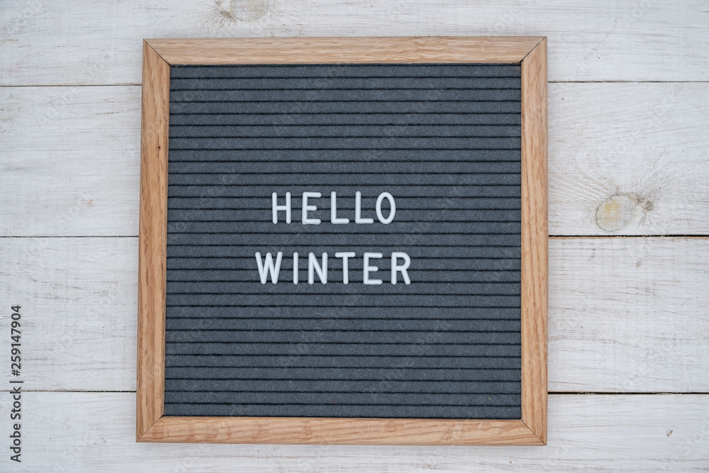 text Hello winter on wooden letter Board in white letters on grey background