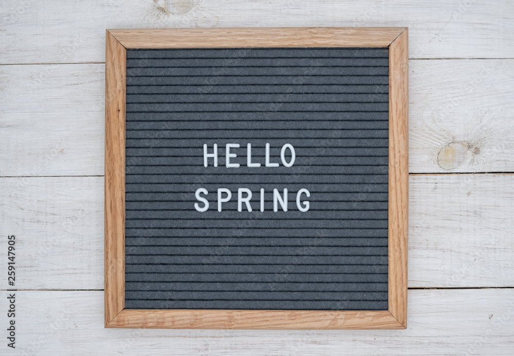 text Hello spring on wooden letter Board in white letters on grey background