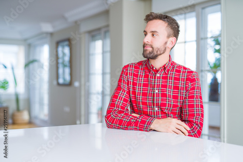 Handsome man wearing colorful shirt smiling looking side and staring away thinking.