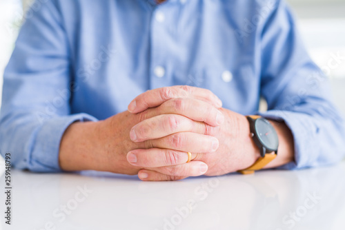 Close up of man hands with crossed fingers over white table
