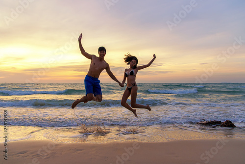 Summer Vacation.  Couple jumping holding hands on tropical on the beach sunset time in holiday trips.  Honeymoon holidays people relaxing together on summer travel destination.  Summer  Travel 