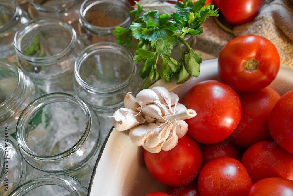 Canning fresh tomatoes with onions in jelly marinade. Woman hands putting red ripe tomato slices and onion rings in jars. Basil, parsley leaves on top of onions. Vegetable salads for winter