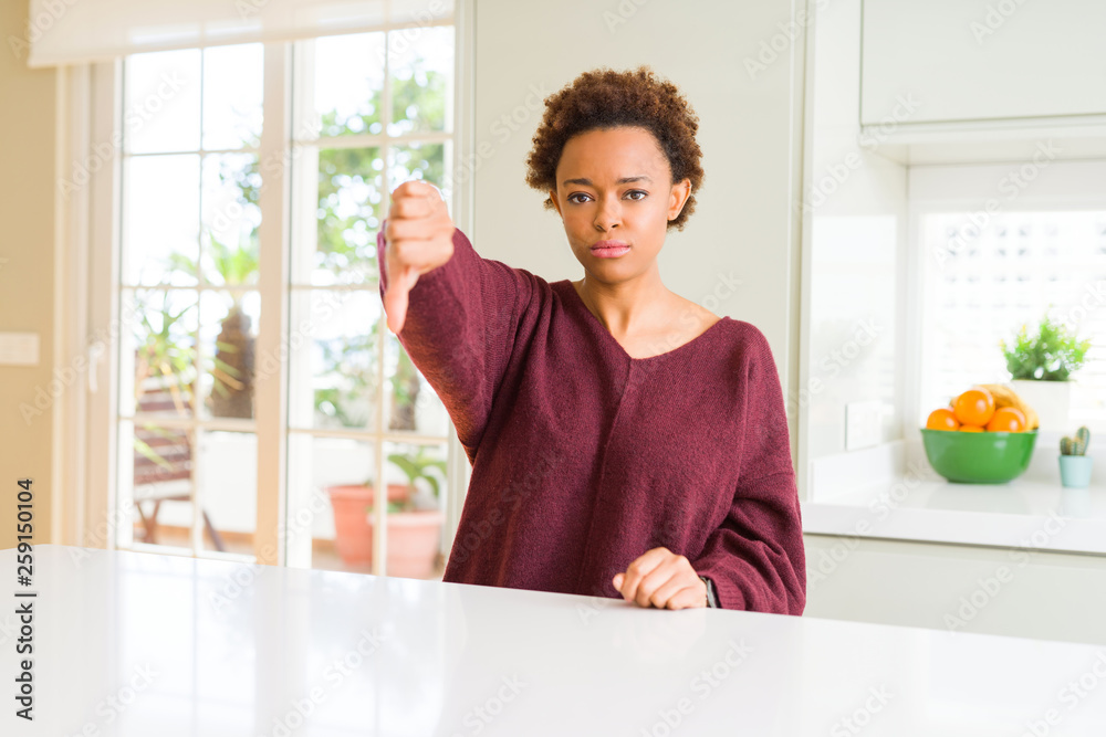 Young beautiful african american woman at home looking unhappy and angry showing rejection and negative with thumbs down gesture. Bad expression. Young beautiful african american woman at home looking unhappy and angry showing rejection and negative with thumbs down gesture. Bad expression.
