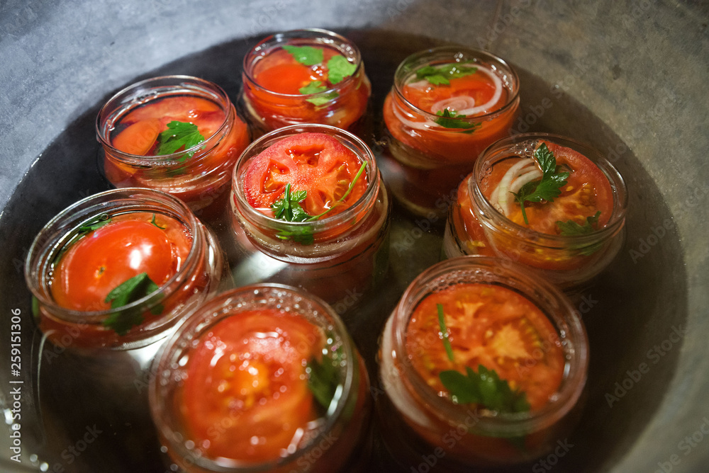 Canning fresh tomatoes with onions in jelly marinade. Conservation and cooking. Jars boiling in water to kill bacteria. Sealing process. Basil, parsley leaves on top. Vegetable salads for winter Canning fresh tomatoes with onions in jelly marinade. Conservation and cooking. Jars boiling in water to kill bacteria. Sealing process. Basil, parsley leaves on top. Vegetable salads for winter