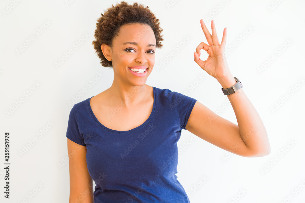 Young beautiful african american woman over white background smiling positive doing ok sign with hand and fingers. Successful expression. Young beautiful african american woman over white background smiling positive doing ok sign with hand and fingers. Successful expression.