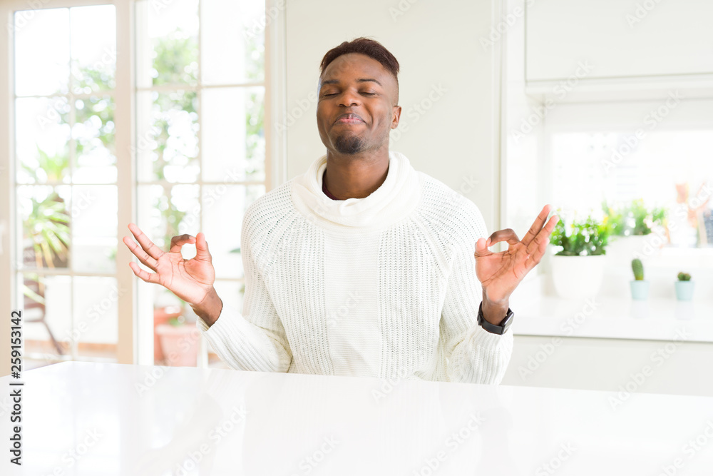 Handsome african american man on white table relax and smiling with eyes closed doing meditation gesture with fingers. Yoga concept. Handsome african american man on white table relax and smiling with eyes closed doing meditation gesture with fingers. Yoga concept.