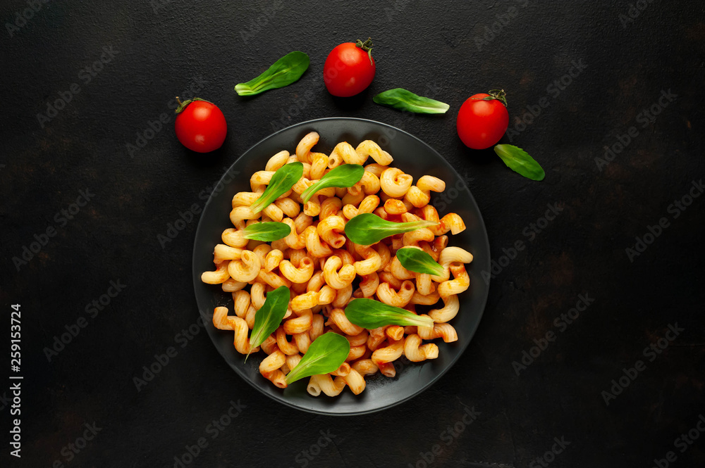 Delicious Italian pasta with tomato sauce, on a plate on a dark table. View from above