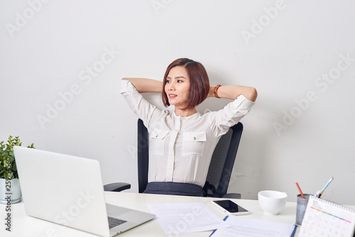 Business woman resting in the office after a working day leaning back her hands behind her head photo