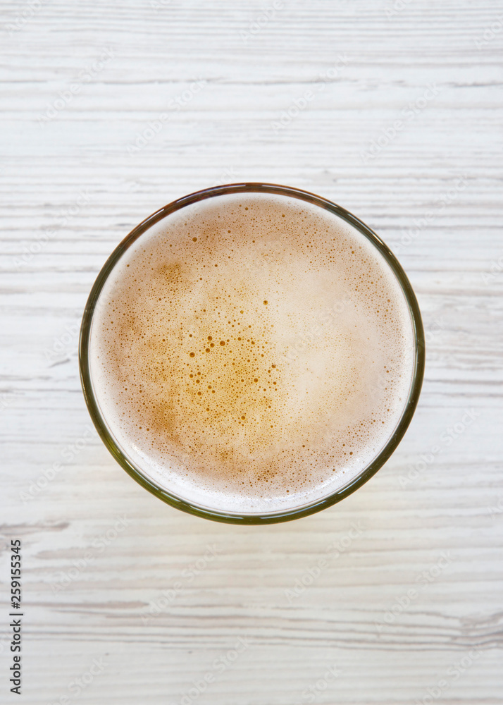 Glass of light beer over white wooden surface, top view. Overhead. Glass of light beer over white wooden surface, top view. Overhead.