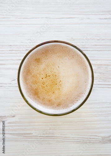 Glass of light beer over white wooden surface, top view. Overhead.