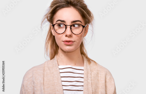 Photography Indoor studio shot of beautiful pensive female with ponytail, looks aside, think