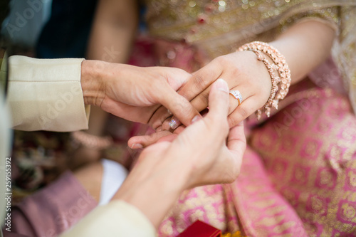 Fotografie groom wears ring on bride's finger in wedding Thailand ceremony