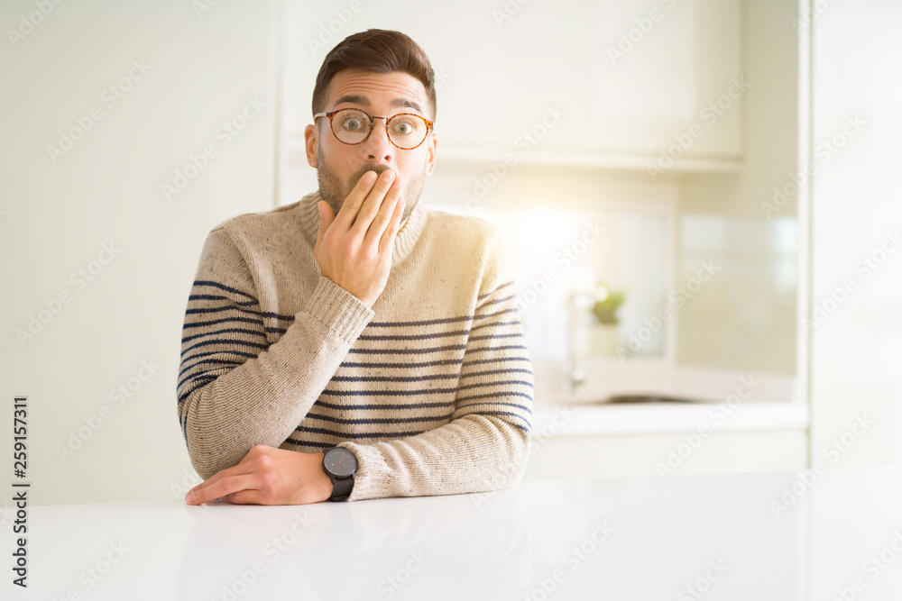 Young handsome man wearing glasses at home cover mouth with hand shocked with shame for mistake, expression of fear, scared in silence, secret concept Young handsome man wearing glasses at home cover mouth with hand shocked with shame for mistake, expression of fear, scared in silence, secret concept