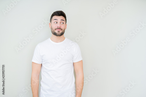 Young handsome man wearing casual white t-shirt over isolated background smiling looking side and staring away thinking.