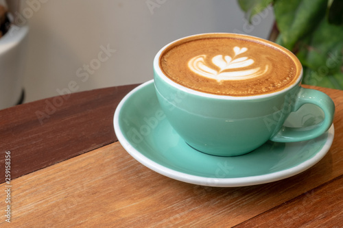 cups of cappuccino with latte art on wooden background. Beautiful foam, greenery ceramic cups, stylish toning, place for text