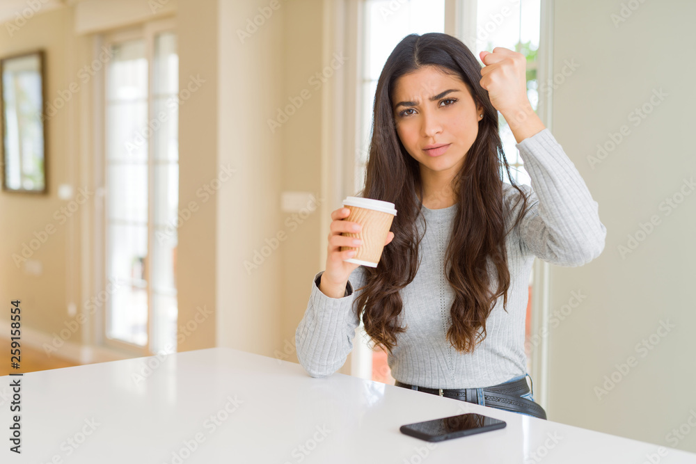 Young woman drinking a cup of coffee at home annoyed and frustrated shouting with anger, crazy and yelling with raised hand, anger concept Young woman drinking a cup of coffee at home annoyed and frustrated shouting with anger, crazy and yelling with raised hand, anger concept