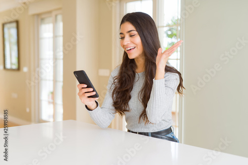 Young woman using smartphone sending a message very happy and excited, winner expression celebrating victory screaming with big smile and raised hands