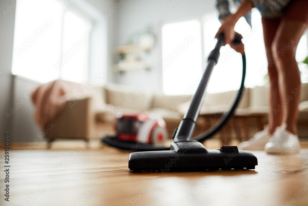 Close-up of unrecognizable woman vacuuming floor at home - obrazy, fototapety, plakaty 