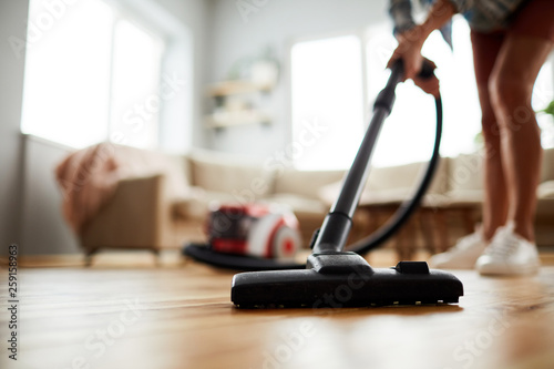 Close-up of unrecognizable woman vacuuming floor at home photo
