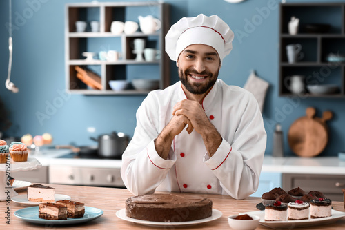 Male confectioner with tasty chocolate cake in kitchen photo