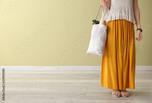 Young woman with fresh products in eco bag indoors
