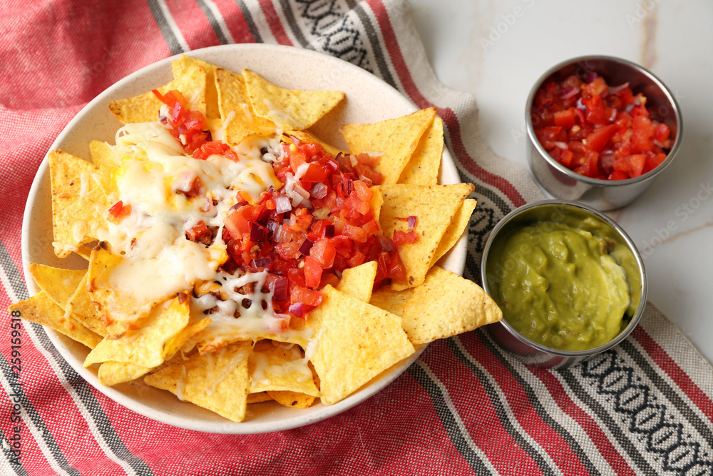 Plate with tasty nachos, cheese, minced meat and salsa on table Plate with tasty nachos, cheese, minced meat and salsa on table