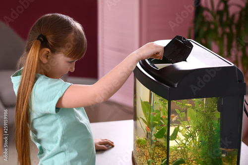 Canvas Print Cute little girl feeding fish in aquarium