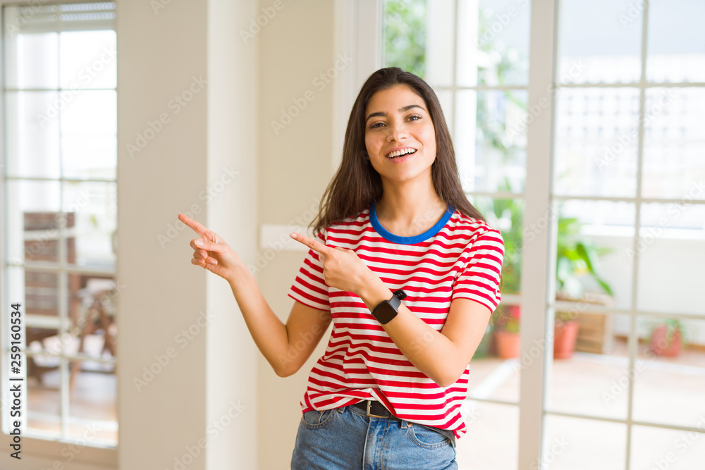 Beautiful young woman smiling cheerful pointing to the side with fingers