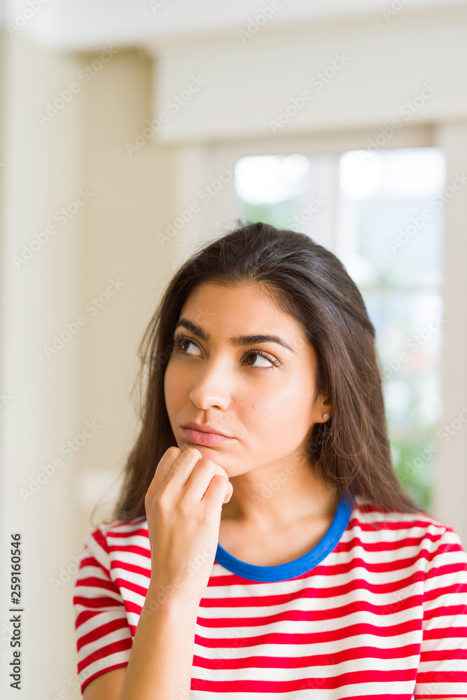 Young beautiful woman thinking and wondering with a hand on chin, doubt concept Young beautiful woman thinking and wondering with a hand on chin, doubt concept