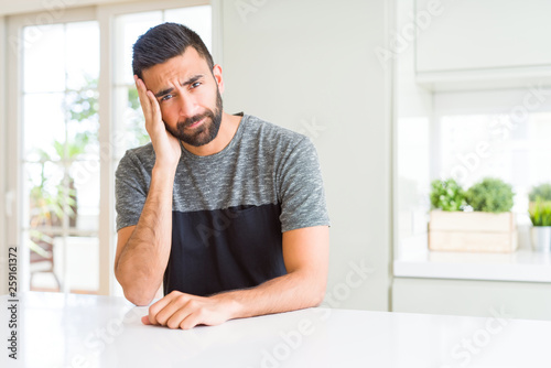 Handsome hispanic man wearing casual t-shirt at home thinking looking tired and bored with depression problems with crossed arms. © Krakenimages.com