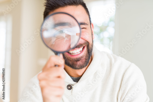 Handsome man using magnifying glass, doing funny faces