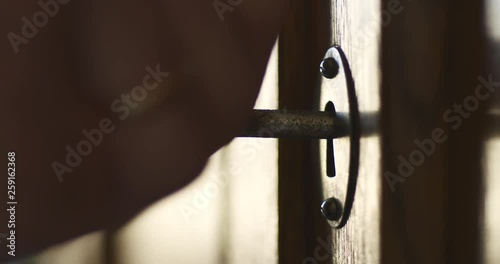 Side wiev of person by hand turns old key in the keyhole of antique wooden cabinet