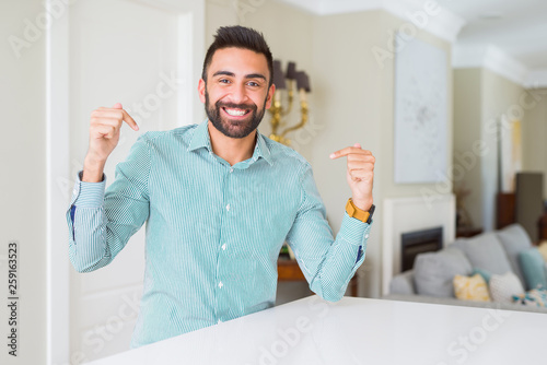 Handsome hispanic man at home looking confident with smile on face, pointing oneself with fingers proud and happy.