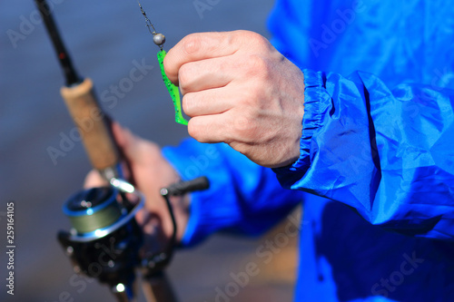 Fisherman holds spinning and bait close up. Fishing