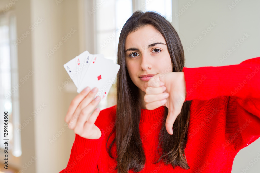 Beautiful young woman gambling playing poker with angry face, negative sign showing dislike with thumbs down, rejection concept Beautiful young woman gambling playing poker with angry face, negative sign showing dislike with thumbs down, rejection concept