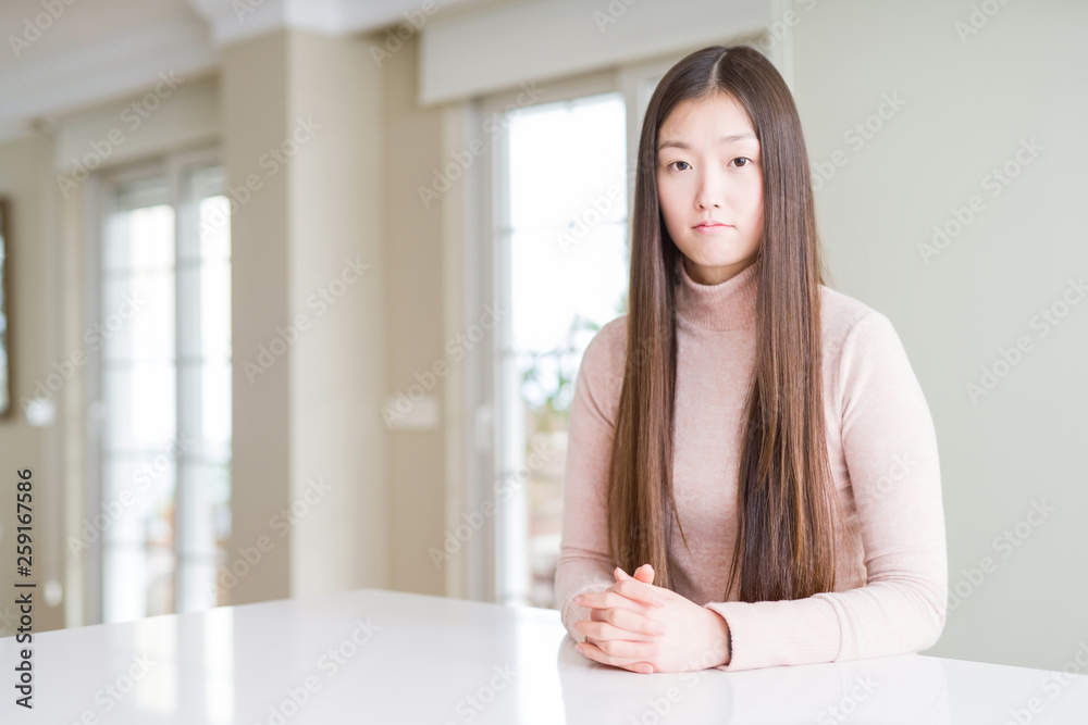Beautiful Asian woman wearing casual sweater on white table depressed and worry for distress, crying angry and afraid. Sad expression. Beautiful Asian woman wearing casual sweater on white table depressed and worry for distress, crying angry and afraid. Sad expression.