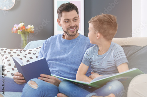 Father and son reading books together at home