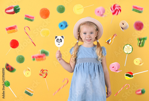 Cute little girl with candy on color background
